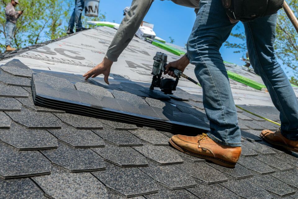 Professional roofing crew installing gray architectural composition shingles on a commercial facility in Salt Lake City.